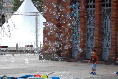 Barselona 'da bir parkta dev sabun köpükleri yapan bir sokak şarkıcısını izleyen turistler
