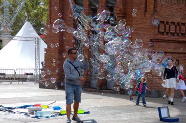 Barselona 'da bir parkta dev sabun köpükleri yapan bir sokak şarkıcısını izleyen turistler