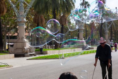 Barselona 'da bir parkta dev sabun köpükleri yapan bir sokak şarkıcısını izleyen turistler