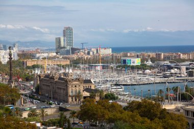 Barselona 'da modern bir binanın üzerinde yükselen üç sanayi bacası bulutlu bir gökyüzünün altında panoramik şehir manzarası sunuyor.