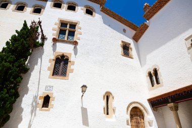 Teslimatçı, güneşli bir günde, İspanya 'da mavi renkli evlerin olduğu dar bir sokakta scooter sürüyor.