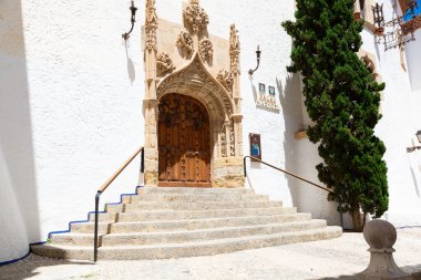 Teslimatçı, güneşli bir günde, İspanya 'da mavi renkli evlerin olduğu dar bir sokakta scooter sürüyor.