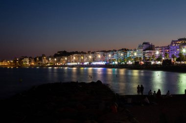 Turistler ve yerliler sahilde bir yaz gecesinin tadını çıkarıyorlar, eğlence gezileri ve canlı müzikle bir festival izliyorlar.