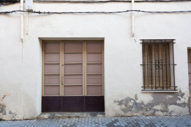 Yıpranmış kırmızı ahşap kapılı, grafiti etiketli, yaş ve çürüme belirtileri gösteren.