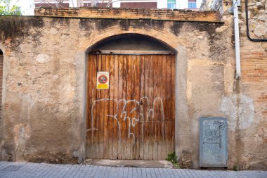 Yıpranmış kırmızı ahşap kapılı, grafiti etiketli, yaş ve çürüme belirtileri gösteren.