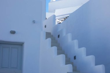 Mavi renkli saksılarda büyüyen küçük bitkiler beyaz bir duvarın basamaklarını süslüyor.