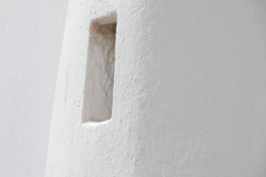 Dikdörtgen şeklinde bir açıklığı olan beyaz bir bacanın mimari ayrıntıları minimalist ve geometrik bir kompozisyon oluşturur.