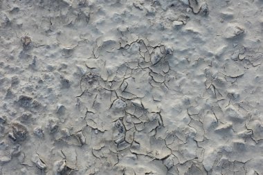 Çatlak toprak dokusu aşırı ısı ve yağmur eksikliğinden kaynaklanan soyut bir model oluşturuyor. Kuraklığı ve iklim değişikliğini simgeliyor.