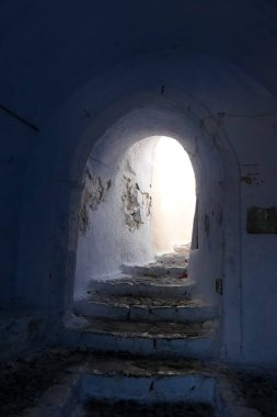 Beyaz boyanmış duvarları, taş kaldırımları olan dar bir tüneli ve Yunanistan 'daki Yunan adalarında büyüleyici bir Akdeniz atmosferi yaratan resimli bir ara sokak.
