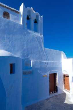 Santorini, Yunanistan 'da bayrak sallayan ve mavi kubbeli geleneksel Yunan Ortodoks Kilisesi