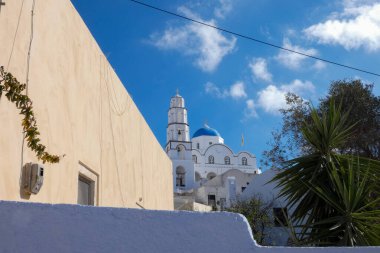 Santorini, Yunanistan 'da bayrak sallayan ve mavi kubbeli geleneksel Yunan Ortodoks Kilisesi