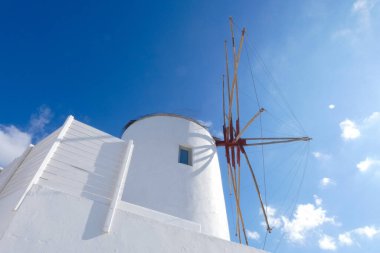 Resimli, bembeyaz, mavi gökyüzüne karşı dimdik duran yel değirmeni geleneksel Yunan mimarisi ve ada cazibesini sergiliyor.