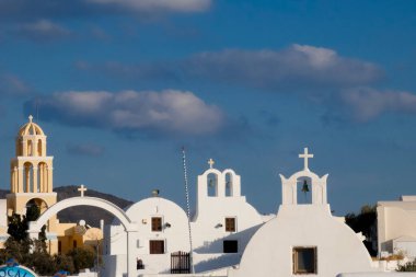 Beyaz boyanmış evler ve mavi kubbeli kiliseler Oia, Santorini, Yunanistan 'da pitoresk bir şehir manzarası yaratıyor.