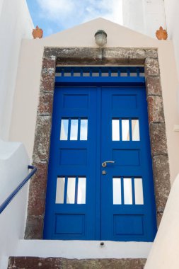 Açık mavi ahşap kapılı oval pencereli ve Yunanistan 'da beyazlatılmış bir evde fener.