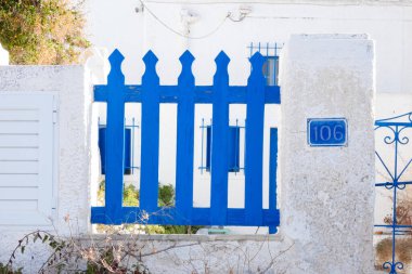 Canlı mavi bahçe çitleri ve Yunan 'da geleneksel beyaz boyalı bir evin önündeki kapı karakteristik mimariyi gözler önüne seriyor.
