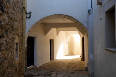 Beyaz boyanmış duvarları, taş kaldırımları olan dar bir tüneli ve Yunanistan 'daki Yunan adalarında büyüleyici bir Akdeniz atmosferi yaratan resimli bir ara sokak.