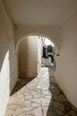 Beyaz boyanmış duvarları, taş kaldırımları olan dar bir tüneli ve Yunanistan 'daki Yunan adalarında büyüleyici bir Akdeniz atmosferi yaratan resimli bir ara sokak.
