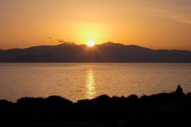 Sokak lambaları, renkli bulutlarla dolu güzel bir günbatımı gökyüzüne karşı siluetler oluşturur.