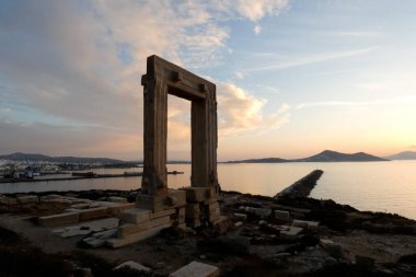 Antik portara, mermer bir kapı, Yunanistan 'ın Naxos adasındaki saray adasında duruyor, Ege Denizi ve günbatımında Chora kasabasının çarpıcı manzarasını sunuyor.