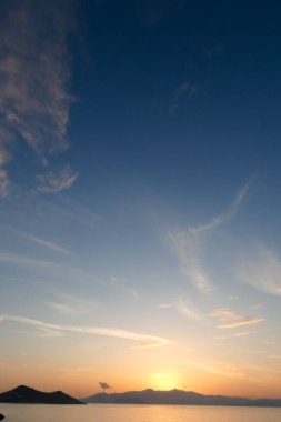 Sokak lambaları, renkli bulutlarla dolu güzel bir günbatımı gökyüzüne karşı siluetler oluşturur.