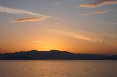Sokak lambaları, renkli bulutlarla dolu güzel bir günbatımı gökyüzüne karşı siluetler oluşturur.