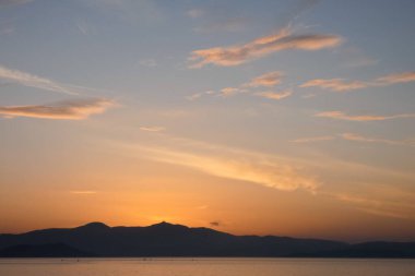 Sokak lambaları, renkli bulutlarla dolu güzel bir günbatımı gökyüzüne karşı siluetler oluşturur.