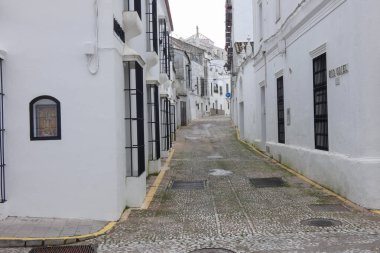 Aracena, Huelva, Endülüs, İspanya 'daki beyaz binalar arasında yokuş yukarı giden dar bir kaldırım taşı caddesi.