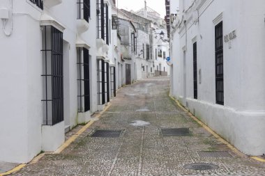 Aracena, Huelva, Endülüs, İspanya 'daki beyaz binalar arasında yokuş yukarı giden dar bir kaldırım taşı caddesi.