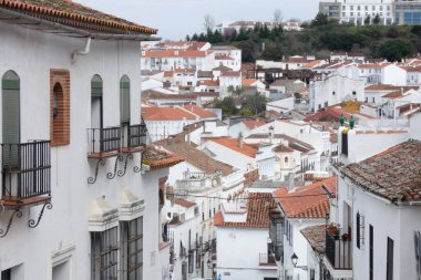 Aracena, Huelva, Endülüs, İspanya 'daki beyaz binalar arasında yokuş yukarı giden dar bir kaldırım taşı caddesi.