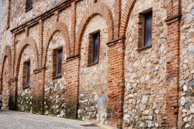 Aracena, Huelva, Endülüs, İspanya 'daki beyaz binalar arasında yokuş yukarı giden dar bir kaldırım taşı caddesi.
