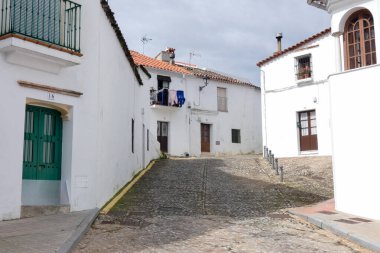 Aracena, Huelva, Endülüs, İspanya 'daki beyaz binalar arasında yokuş yukarı giden dar bir kaldırım taşı caddesi.