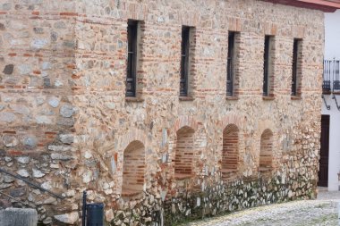 Aracena, Huelva, Endülüs, İspanya 'daki beyaz binalar arasında yokuş yukarı giden dar bir kaldırım taşı caddesi.