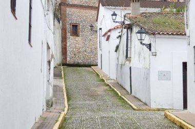 Aracena, Huelva, Endülüs, İspanya 'daki beyaz binalar arasında yokuş yukarı giden dar bir kaldırım taşı caddesi.
