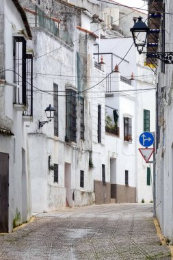 Aracena, Huelva, Endülüs, İspanya 'daki beyaz binalar arasında yokuş yukarı giden dar bir kaldırım taşı caddesi.