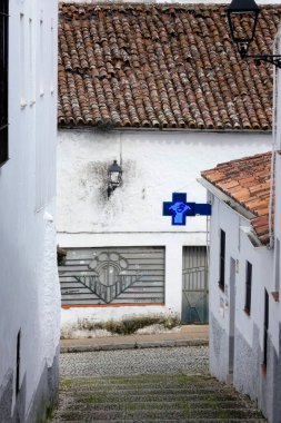 Aracena, Huelva, Endülüs, İspanya 'daki beyaz binalar arasında yokuş yukarı giden dar bir kaldırım taşı caddesi.