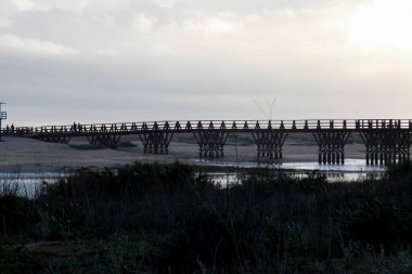 İspanya 'nın Cristina Adası Huelva şehrinde nehrin iki yakasını birbirine bağlayan uzun tahta bir köprü.