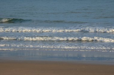 Okyanus dalgaları, bulutlu bir günde dalgalı suların yakınındaki kayalara çarpar ve dramatik bir deniz manzarası yaratır.