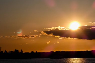 Kuşlar güzel bir altın saat boyunca uçuyor. Karanlık bulutlar ve parlak merceklerle gün batımında.