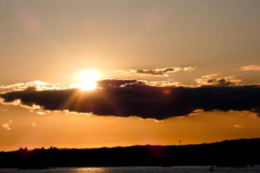 Kuşlar güzel bir altın saat boyunca uçuyor. Karanlık bulutlar ve parlak merceklerle gün batımında.