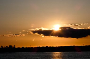 Kuşlar güzel bir altın saat boyunca uçuyor. Karanlık bulutlar ve parlak merceklerle gün batımında.