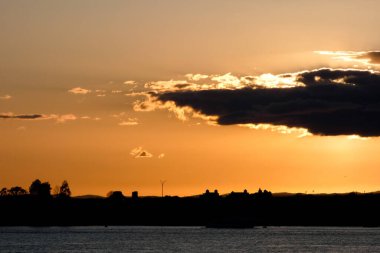 Kuşlar güzel bir altın saat boyunca uçuyor. Karanlık bulutlar ve parlak merceklerle gün batımında.