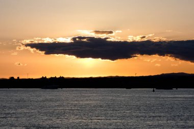 Kuşlar güzel bir altın saat boyunca uçuyor. Karanlık bulutlar ve parlak merceklerle gün batımında.