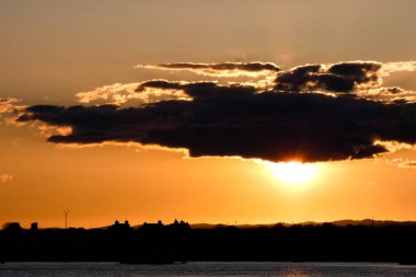 Kuşlar güzel bir altın saat boyunca uçuyor. Karanlık bulutlar ve parlak merceklerle gün batımında.