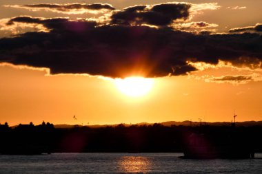 Kuşlar güzel bir altın saat boyunca uçuyor. Karanlık bulutlar ve parlak merceklerle gün batımında.