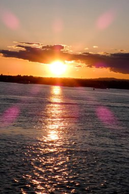 Kuşlar güzel bir altın saat boyunca uçuyor. Karanlık bulutlar ve parlak merceklerle gün batımında.