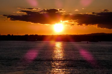 Kuşlar güzel bir altın saat boyunca uçuyor. Karanlık bulutlar ve parlak merceklerle gün batımında.