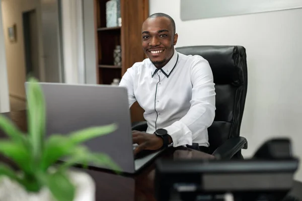 Egy Mosolygó Afrikai Üzletember Irodájában Kamerába Néz Miközben Egy Vezeték — Stock Fotó