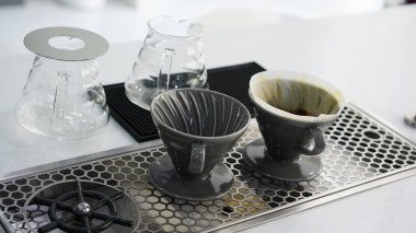 Elinde kahve damlatan moka demliğinden kahve var. Barista çaydanlık ve geleneksel damlatıcıyla kahve damlatıyor. Aroma kahve dükkanında el yapımı sade kahve.