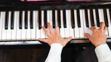 Adult woman plays electronic piano with note sheet. Professional pianist showing solo on acoustic black piano. practicing and learning how to play song. Classic instrument.