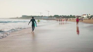 Portekiz, Carcavelos Ekim 2022 sörf tahtalı sörfçüler dalış kıyafeti giymiş kumsalda ağır çekimde yürüyorlar. Aktif su sporu ve tatil eğlence konsepti